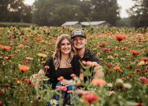 A couple poses together in a vibrant wildflower field filled with colorful blooms.