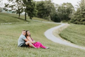 A couple relaxes together on a grassy hillside with winding paths.