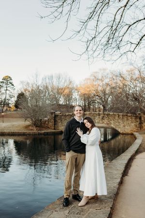 A couple shares tender moments along a lakeside path during a winter engagement session.