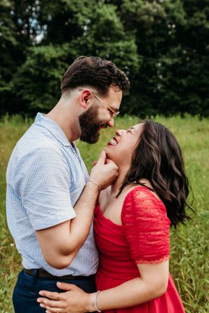 A couple shares an intimate laughing moment in a summer field.