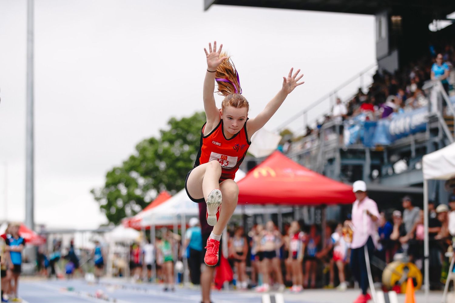 Athlete performing long jump at outdoor track and field competition.