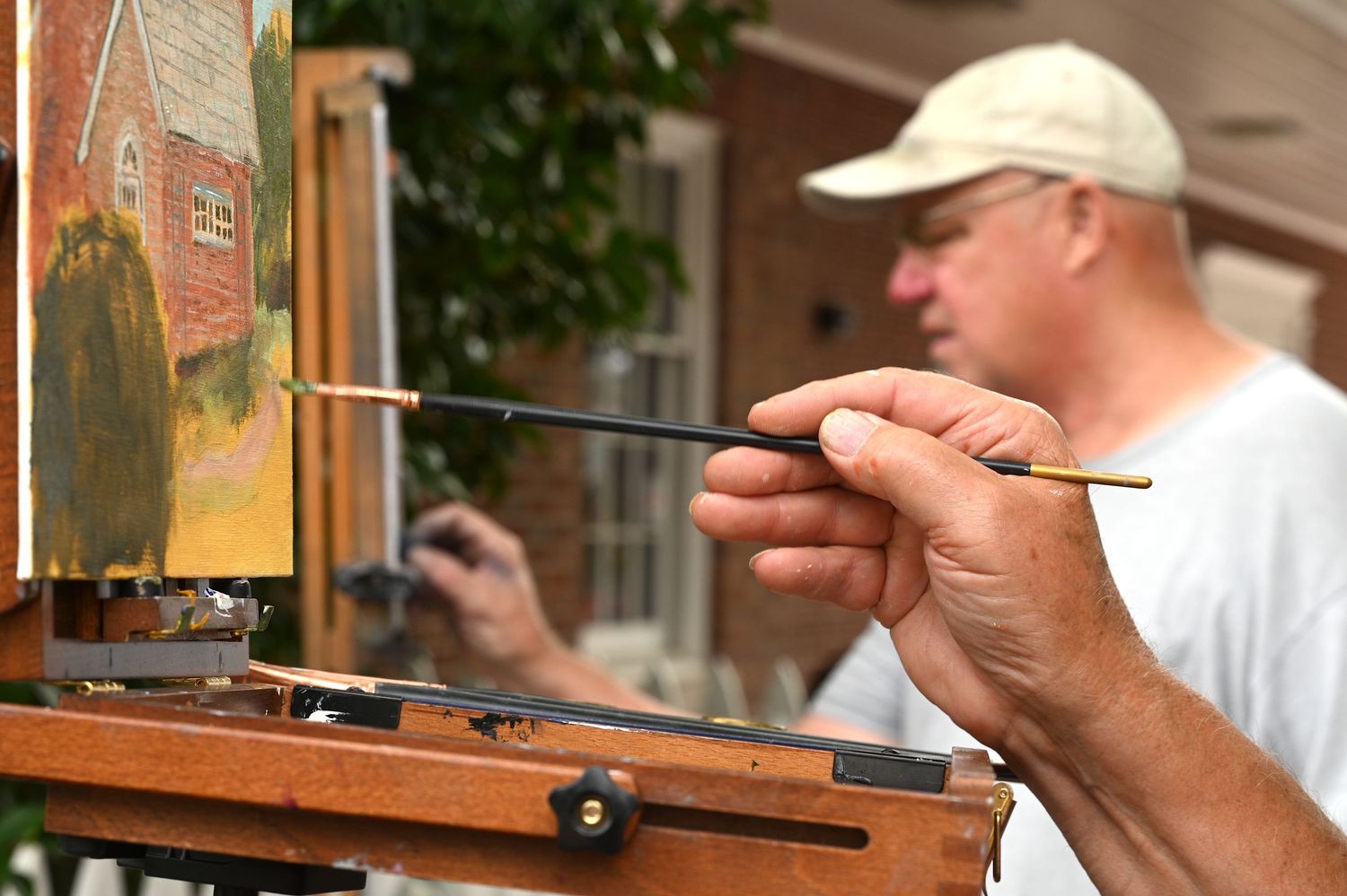 Artist working on a detailed painting using small brushes at an outdoor festival | photo by Tom McCall Photography | Maryland Photographer