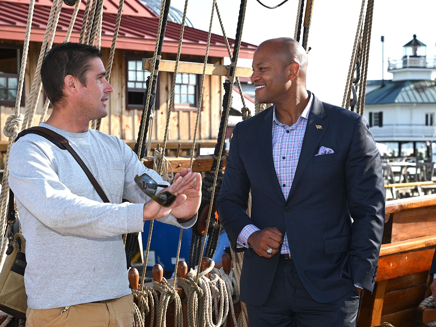 Two men conversing on a boat deck with a lighthouse visible in the background | photo by Tom McCall Photography | Maryland Photographer