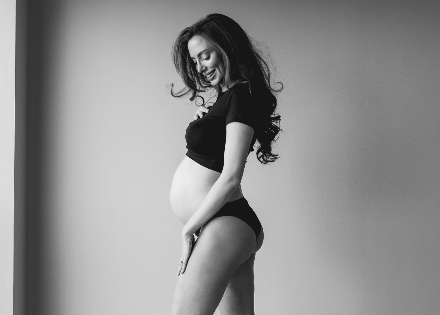 Gravid kvinna ler i villa i Stockholm under fotografering med fokus på närhet
