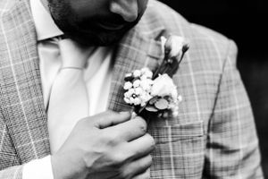 Close-up black and white photo of boutonniere on groom's checkered suit jacket.