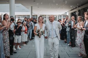 Wedding guests line up outside a modern venue to celebrate with the newlyweds during a summer celebration.