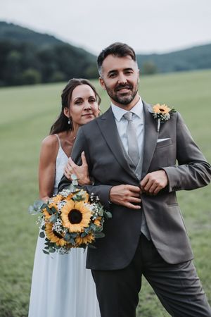 A couple in wedding attire playfully poses in a series of candid shots against a green hillside background.