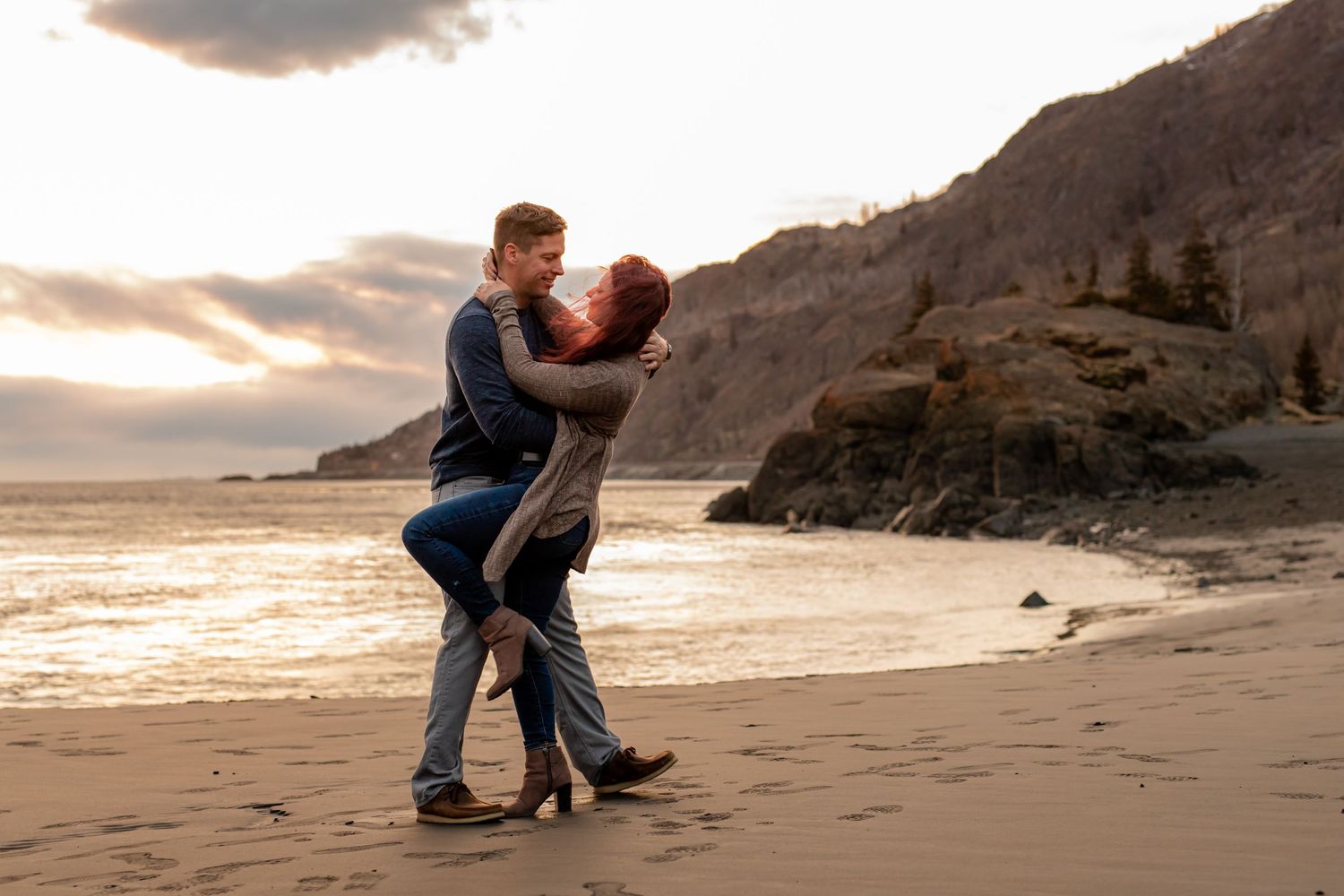 A romantic sunset beach photo with cliffs and ocean waves in the background.