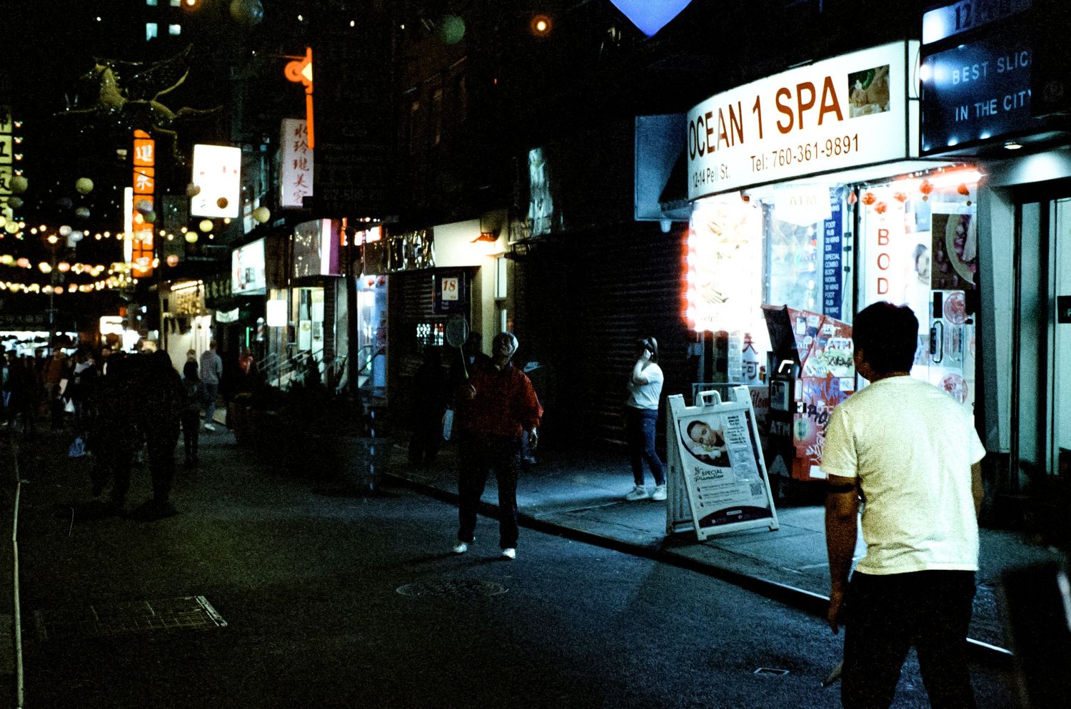 Night scene of an urban street with neon signs and a spa storefront.