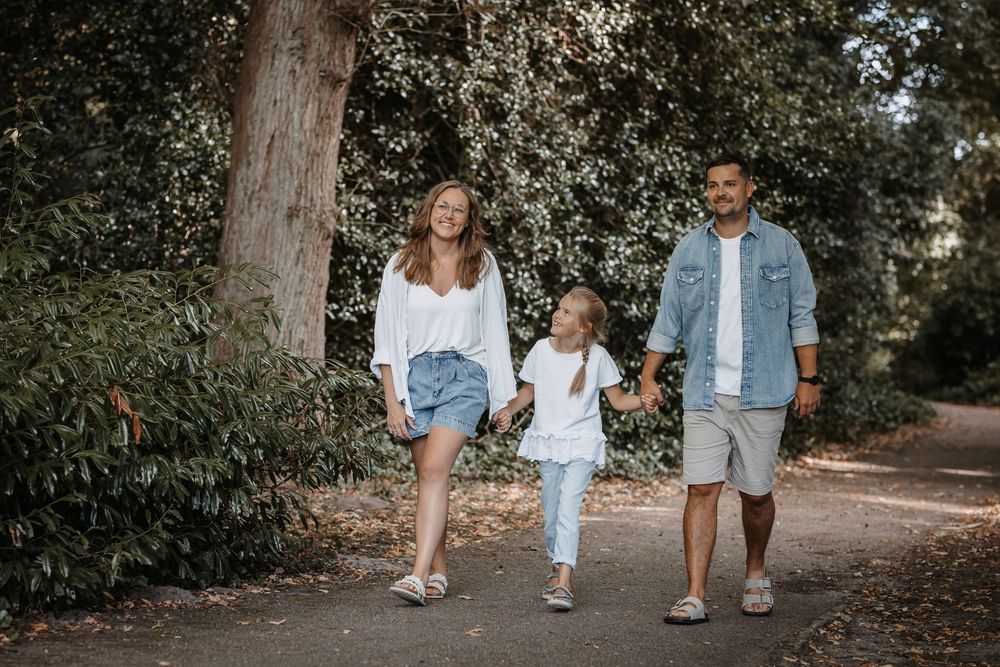 Family taking relaxed stroll together on wooded path.