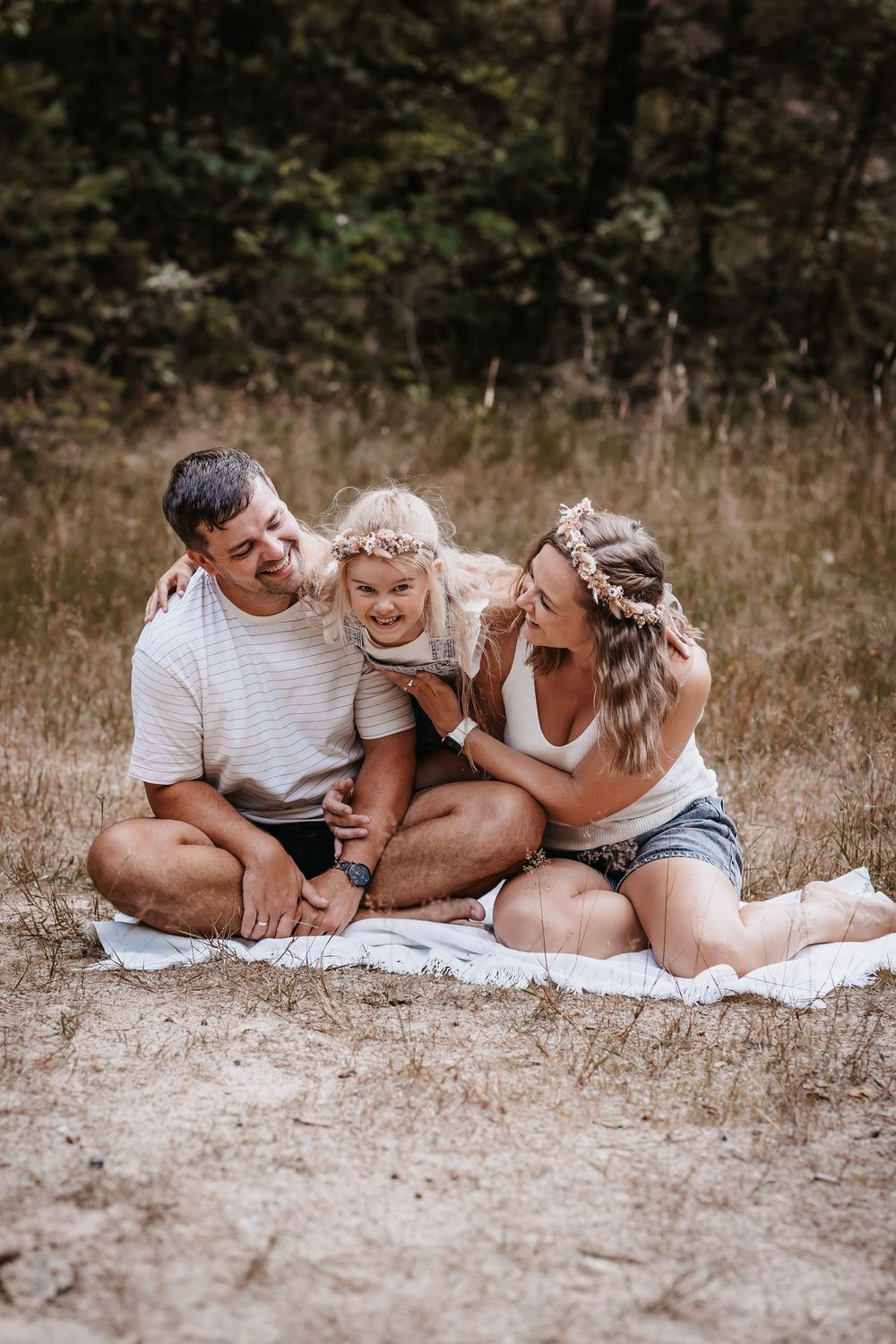 Family lying on blanket outdoors sharing intimate laughs together.