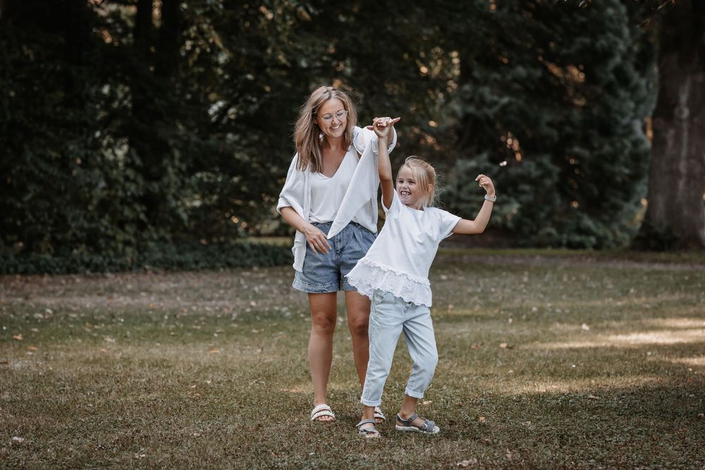 Parent and child playing and dancing together in sunny park.