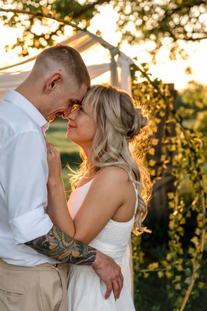 A romantic couple shares an intimate moment at sunset in a vineyard setting with golden light glowing through the vines.