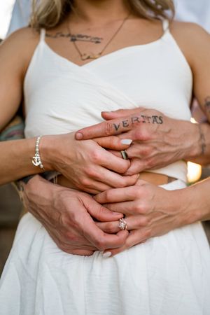 Close-up sequence of hands wearing a white engagement ring against a white dress background.