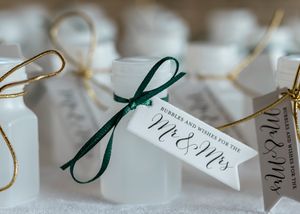Wedding favor bottles decorated with green ribbon and 'Mr & Mrs' tags tied with string for special event reception.