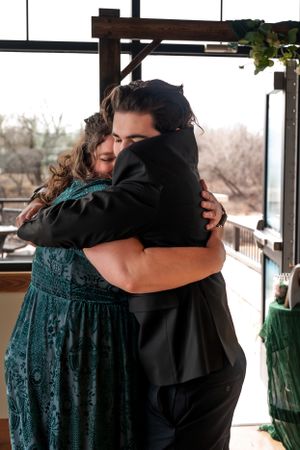 Two people sharing an emotional embrace on a porch with festive decor in the background.