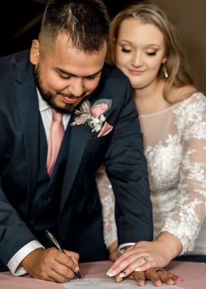 Couple signing their marriage license together at their wedding ceremony.