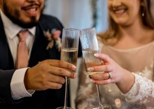 Wedding couple toasts with champagne glasses during their reception celebration.