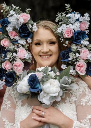A bridal portrait surrounded by a stunning arrangement of blue and pink roses with white accents.