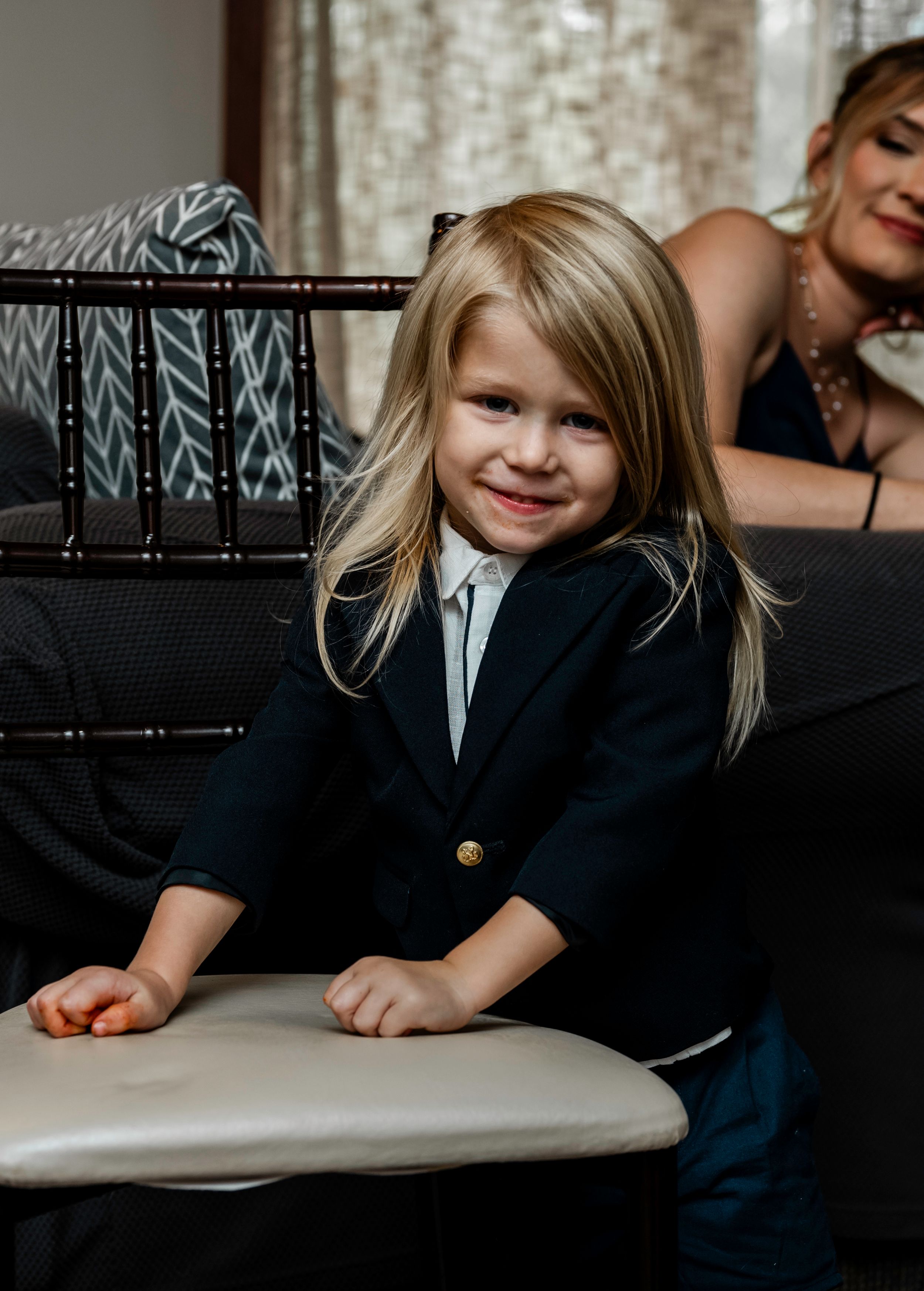 Child wearing a dark jacket sits at table during formal event.