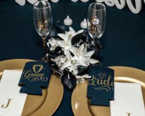 Wedding reception table setting with champagne glasses and custom bride and groom koozies.