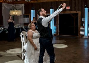 Celebratory moment during a wedding reception as couple raises arms in joy.