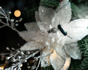 A detailed macro shot of a sparkly white poinsettia decoration with winter elements.