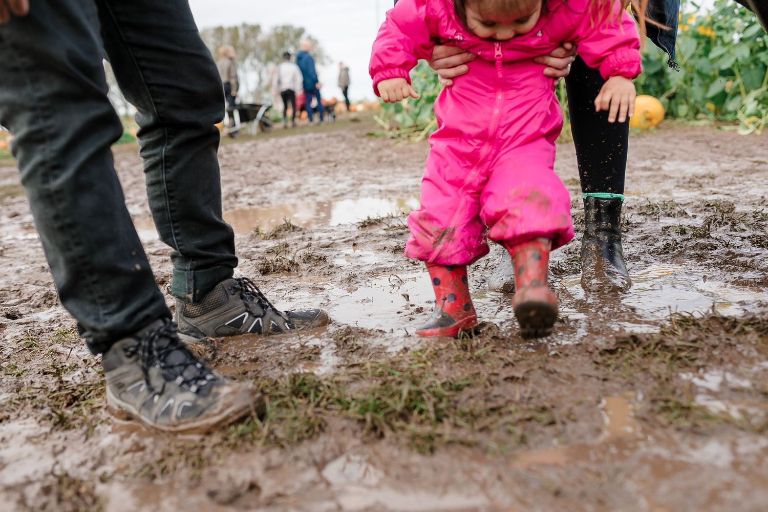 Pink-clad figure splashing through muddy puddles in rubber boots on a rainy day. Photographer. Hull. East Yorkshire. Photography