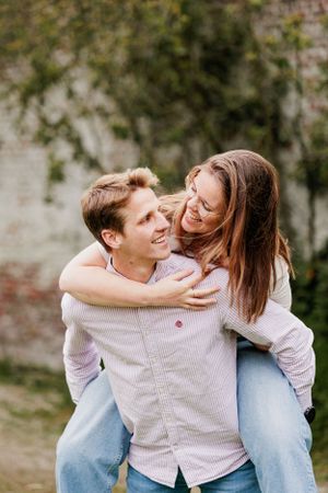 A couple sharing intimate moments and laughter while posing against a stone wall backdrop.