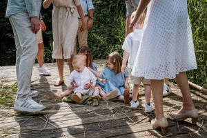Family members' feet and legs shown standing together on wooden planks.