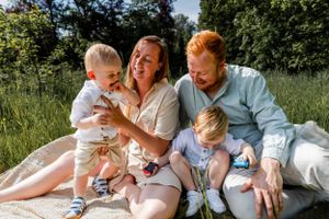 Family lounges together on a blanket during an outdoor photo session in nature.
