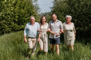 Family members of different generations posed together in a lush green field.