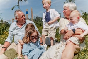 Extended family enjoys a playful outdoor photoshoot together in a sunny field.