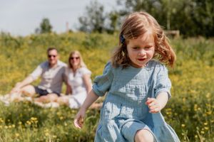Children playing and running through a field of yellow wildflowers on a sunny day.