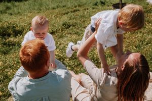 Family members interacting playfully on grass during an outdoor photo session.