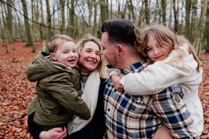 Joyful outdoor family photography session among bare trees and autumn foliage.