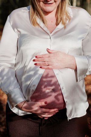 Close-up series of hands cradling a pregnant belly in a white sweater against natural lighting.