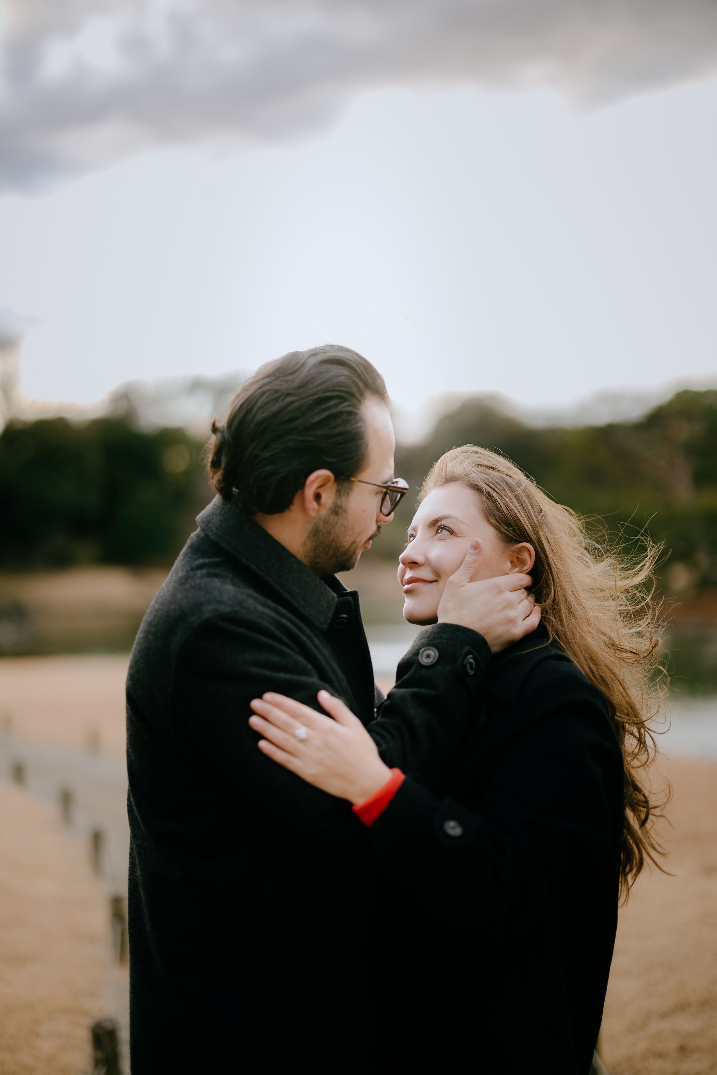 A romantic couple embraces and shares tender moments on a cloudy beach in a series of intimate photographs.