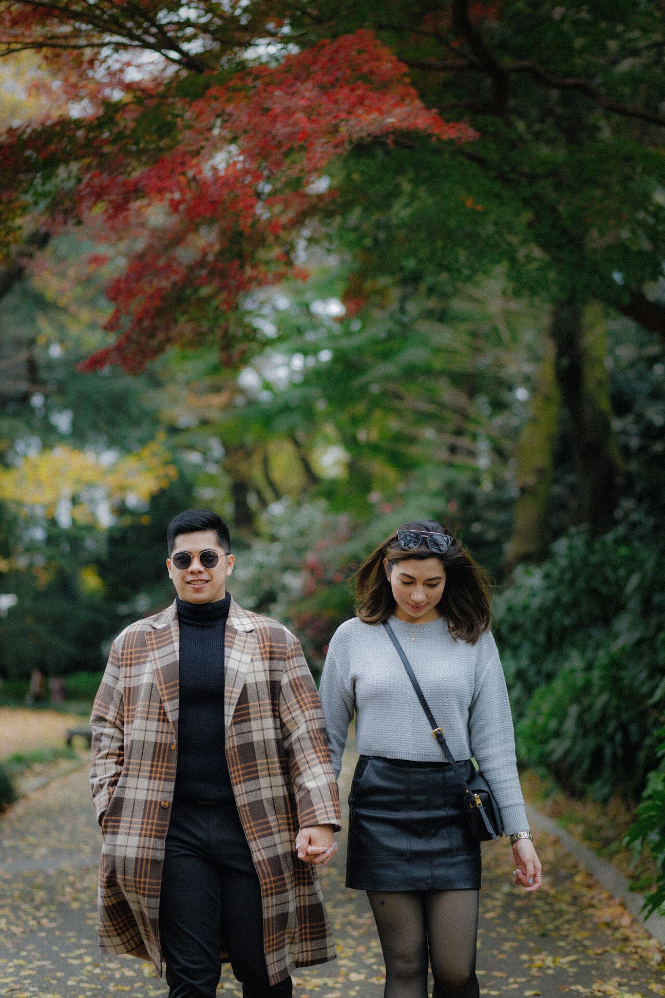 A couple walks along an autumn path with colorful fall foliage overhead.