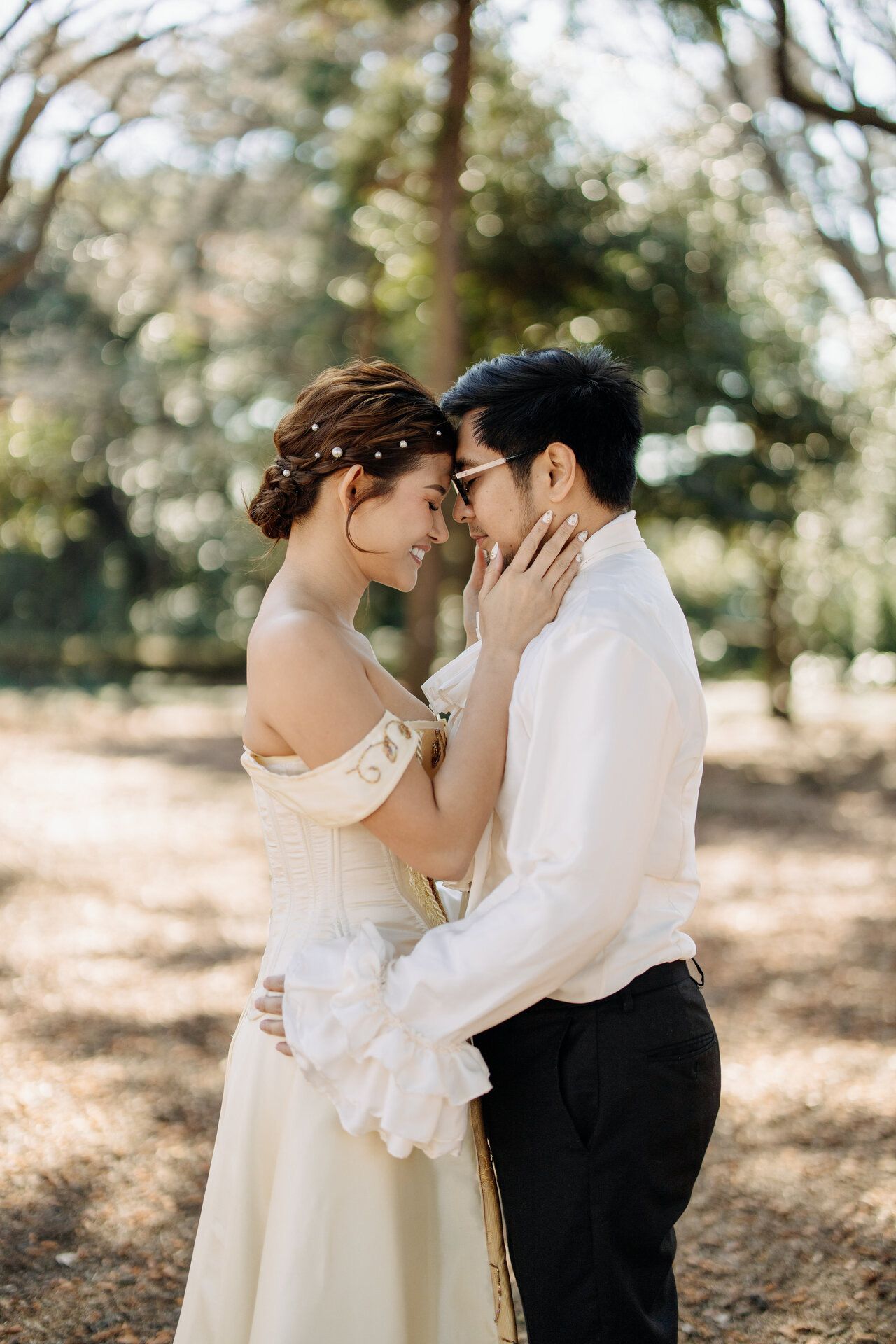 An intimate wedding moment between a couple in a sunlit forest setting.