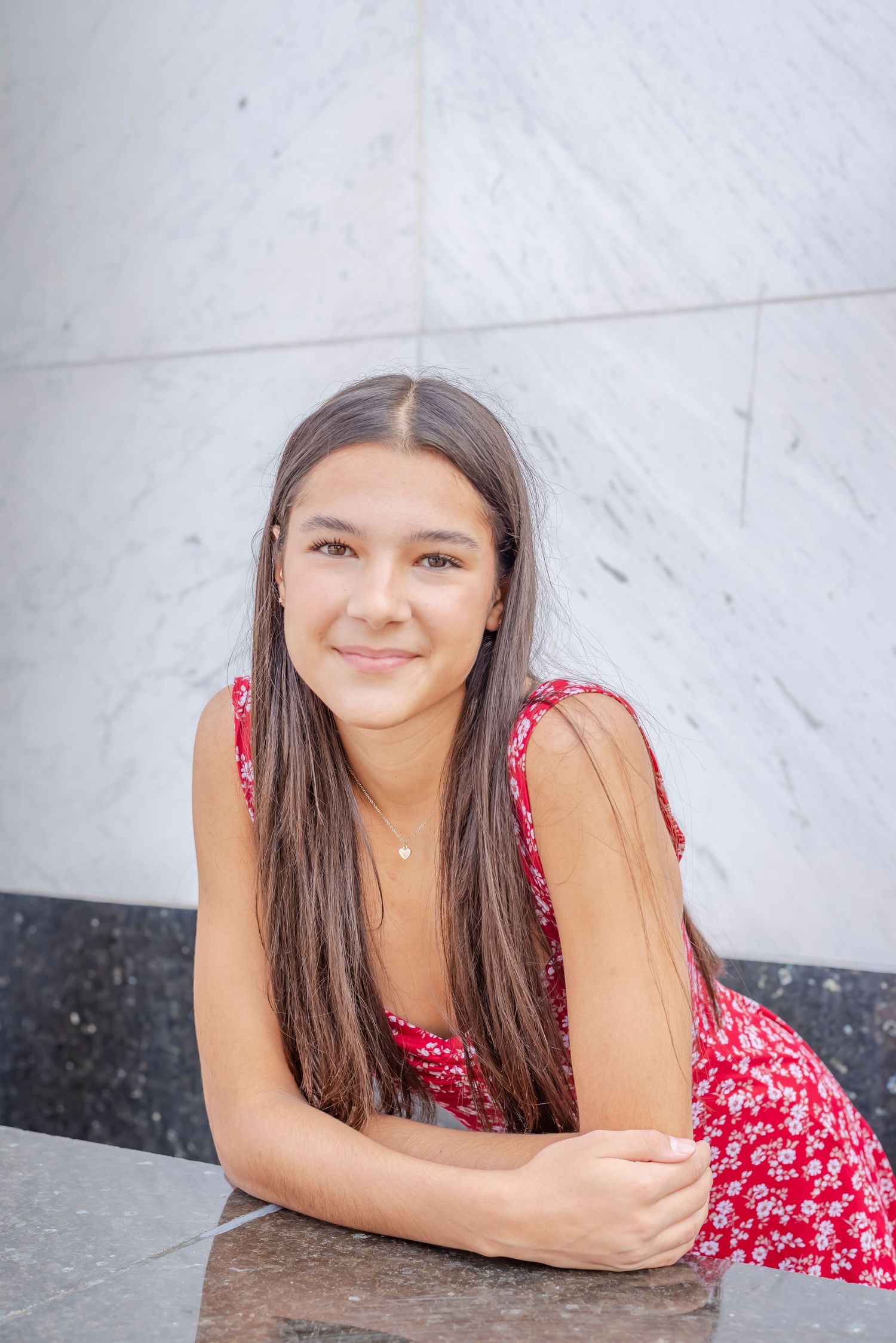 A portrait against a white marble wall background with soft lighting.