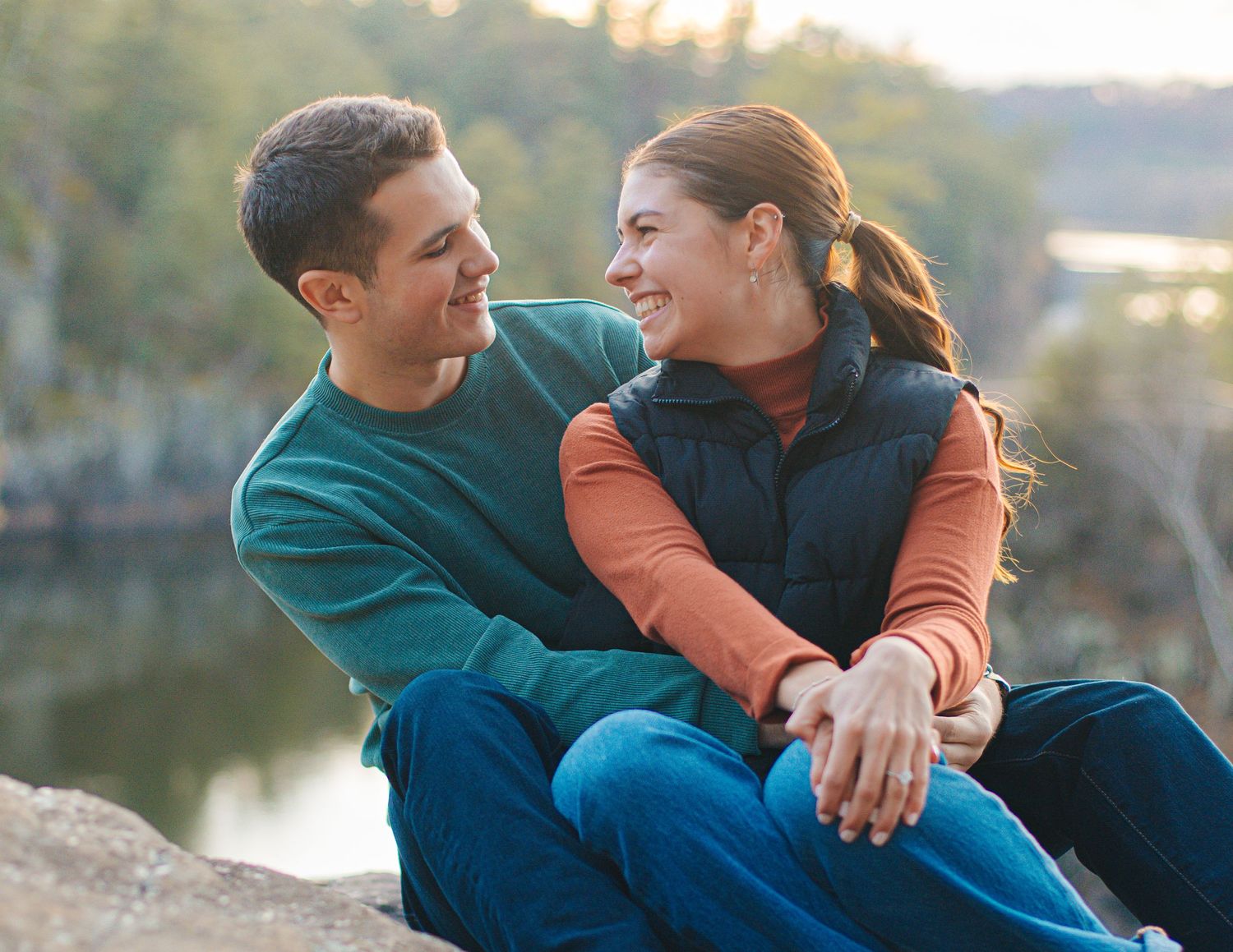 Intimate engagement photos captured by waterfront during sunset.