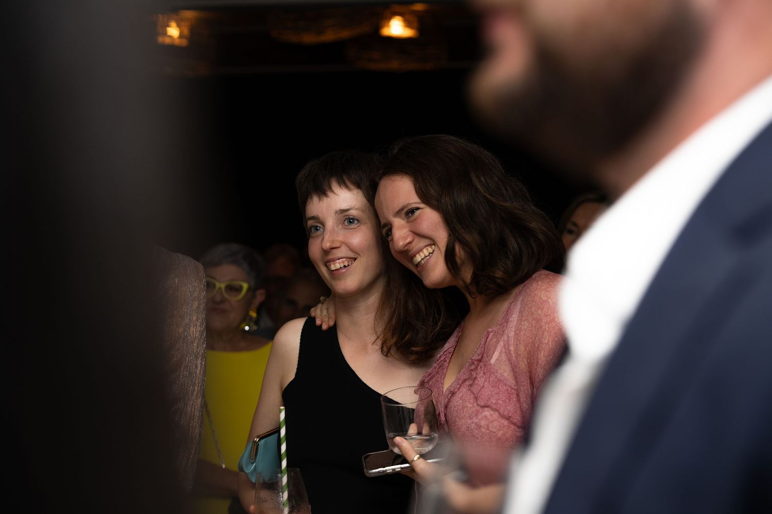 Party guests enjoying themselves in a dimly lit venue.