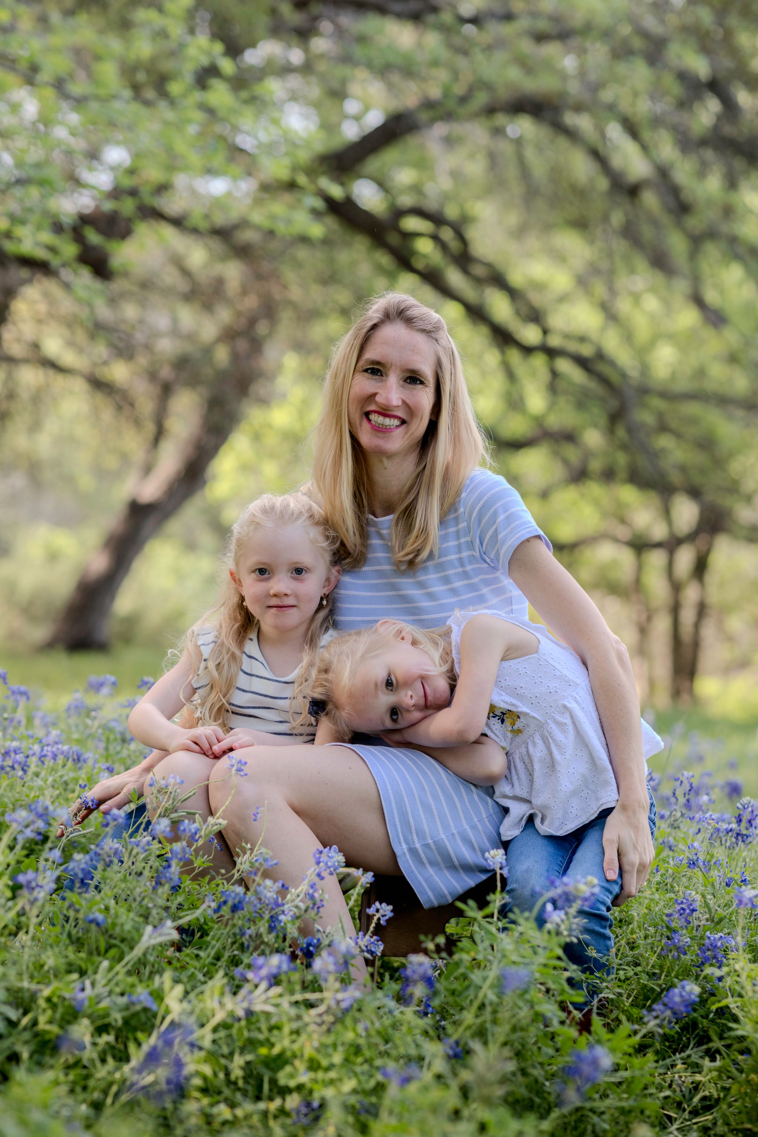 A family enjoys a spring day together sitting among blooming bluebonnets in a park setting. Cedar Park bluebonnet Mini Session
