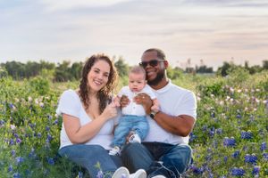 A family sits together in a field of blooming bluebonnets during sunset in Texas. Cedar Park Bluebonnet Mini Session