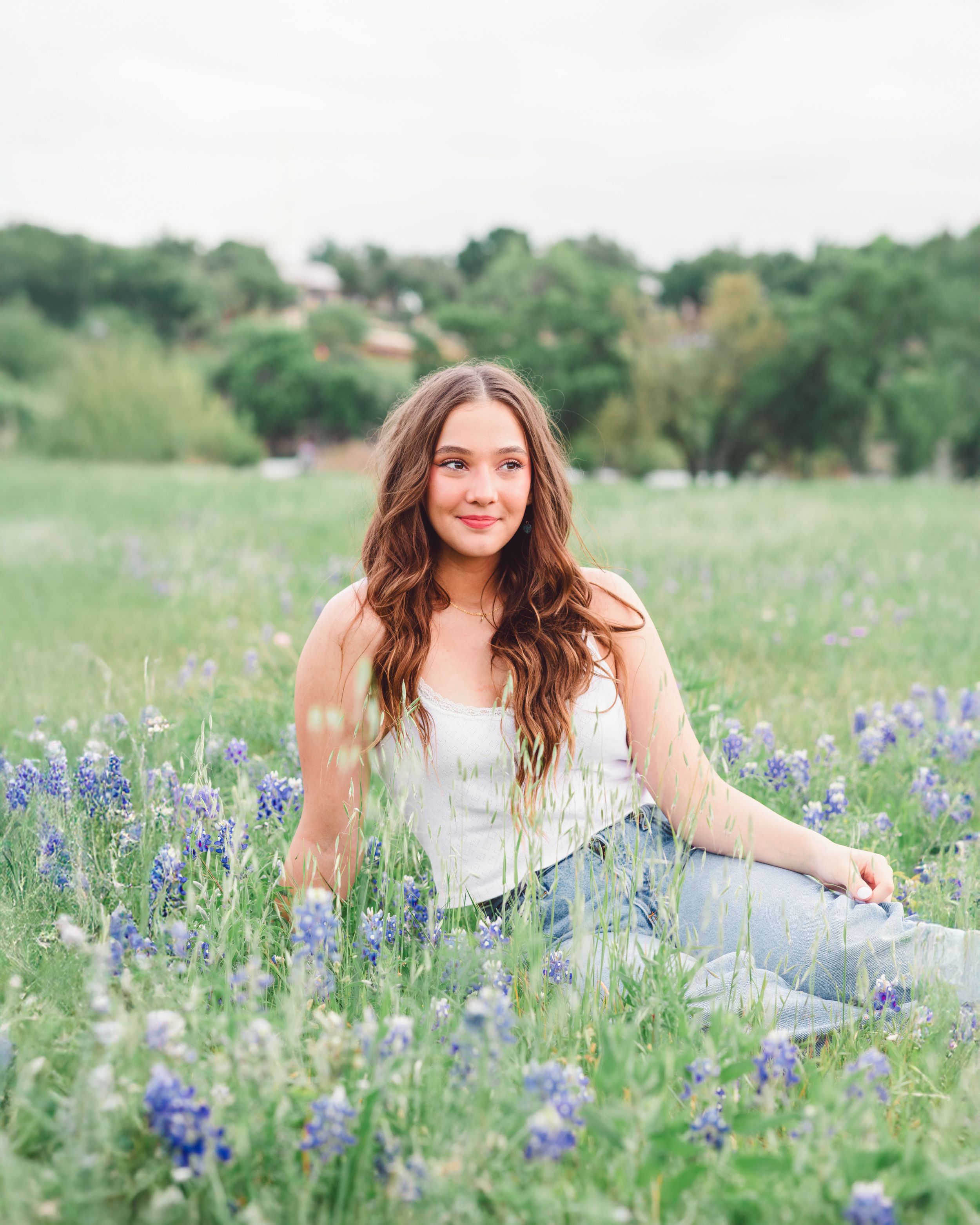 Bluebonnet Mini Sessin Brushy Creek Cedar Park Texas. Senior Photos girl in white tank and jeans poses in the texas bluebonnets in texas