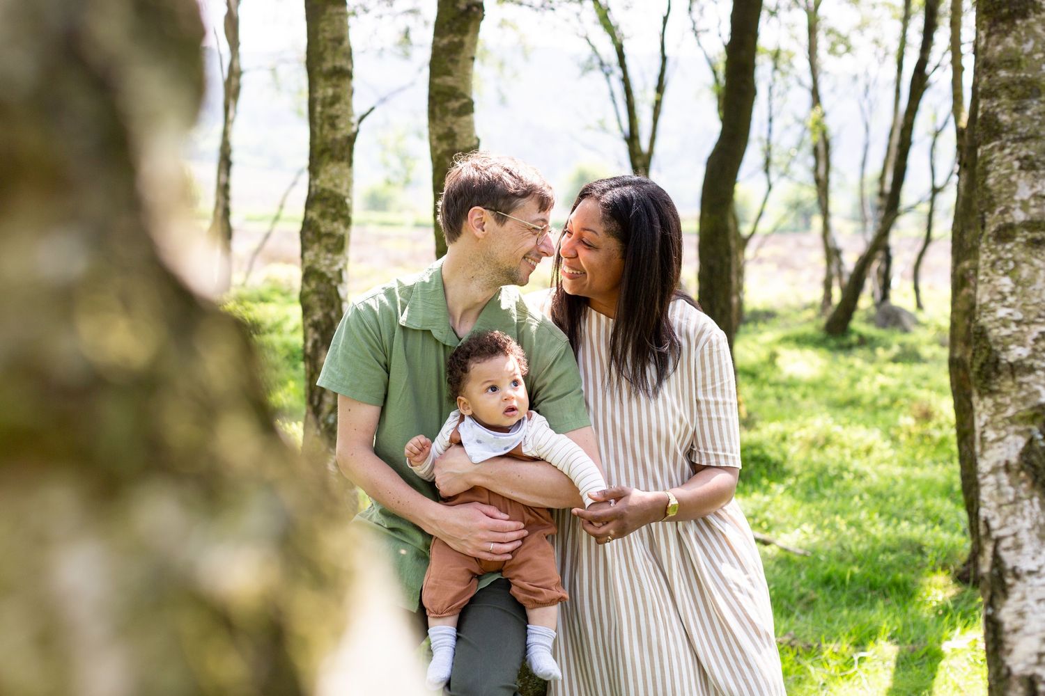 Family sharing tender outdoor moment between birch trees in spring.