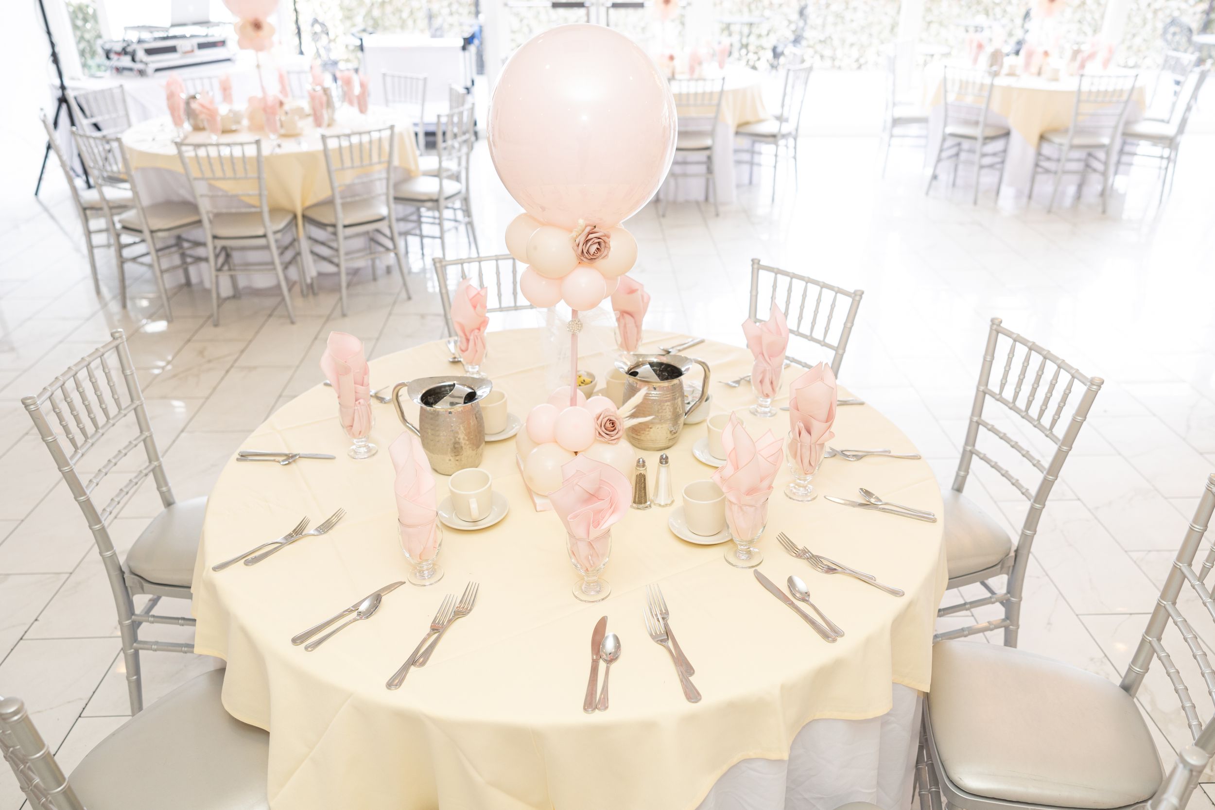 Elegant table setting with pink balloon centerpiece and silver chiavari chairs.