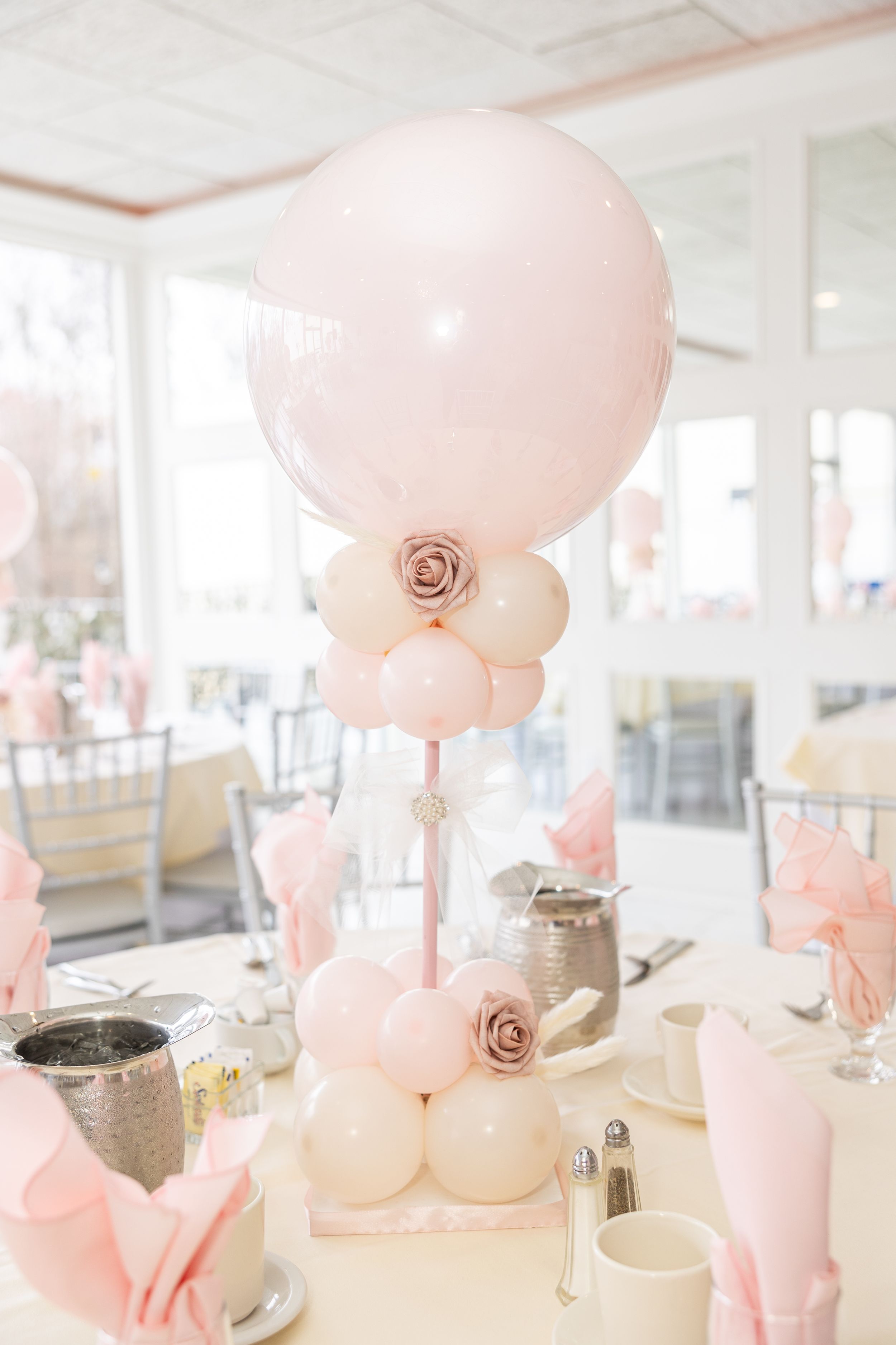 Pink balloon centerpiece with rose accents on formal dining table.