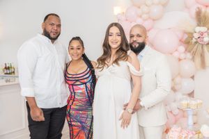 Baby shower celebration with pink balloon arch, white cake, and elegant decorations.